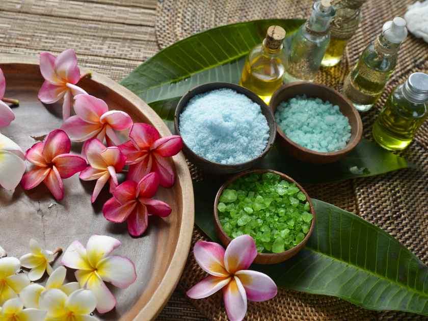 Many Plumeria flower in wooden bowl with green leaf, massage oil ,salt in bowl on mat