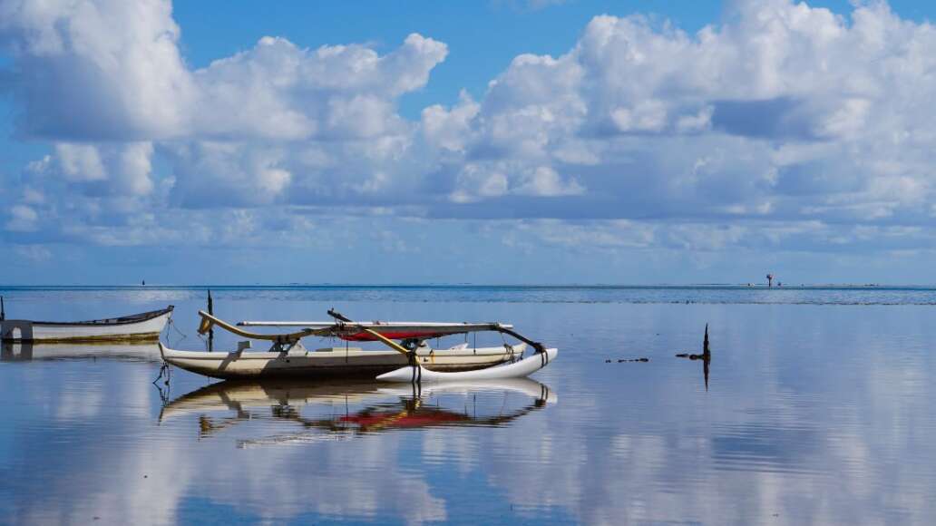 An Outrigger Canoe is Perfectly Mirrored in the Waters of Kaneohe Bay