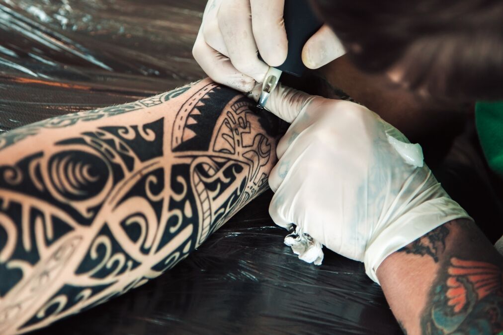 Master tattoo artist in gloves makes polynesian tattoo on hand men