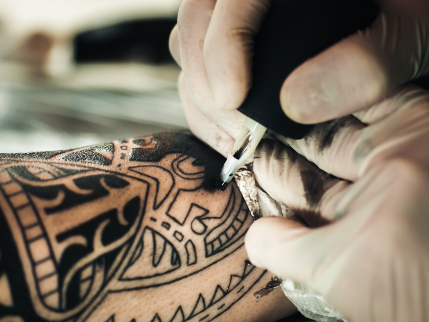 Master tattoo artist in gloves makes polynesian tattoo on hand men