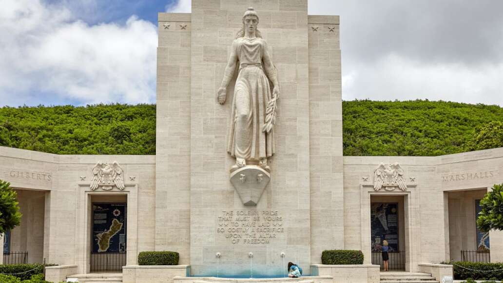 An unidentified woman sits near the fountain monument at National Memorial Cemetery of the Pacific on the island of Oahu, in Hawaii.