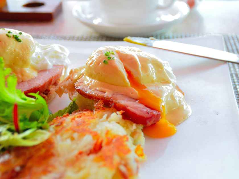 Egg benedict with juicy cut egg as breakfast in Hawaii hotel restaurant.
