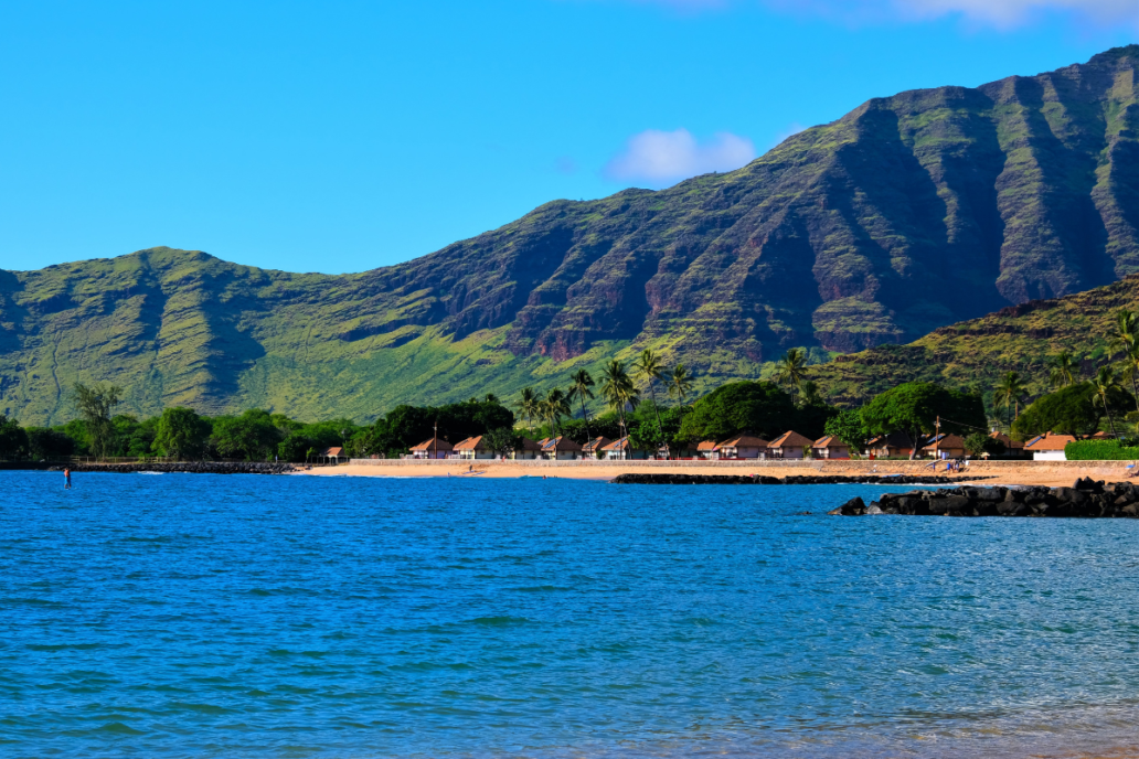 Landscape of the West side of the island of Oahu, Waianae, Hawaii. Pokai Bay beach, coast line, tide pools and Waianae mountain range with palm trees in foreground.